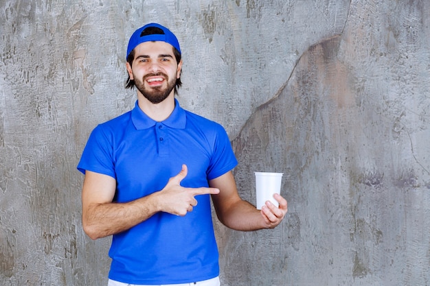 持ち帰り用の飲み物を持っている青い制服を着た男。