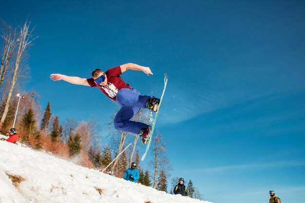 Man boarder jumping on his snowboard against the backdrop of mountains