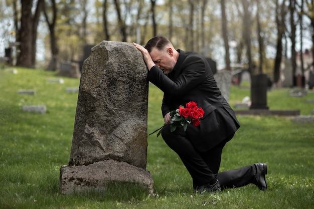 묘지의 묘비에 장미를 가져오는 남자