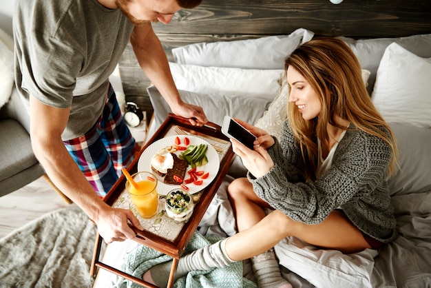 Man bringing woman delicious breakfast