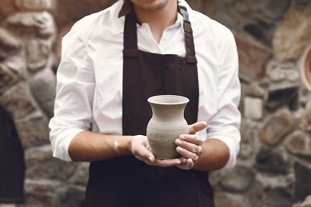 Man in a brown apron standing with a vase