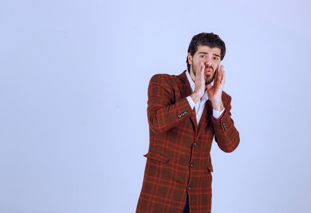 Man in brown blazer closing his face with hands. 