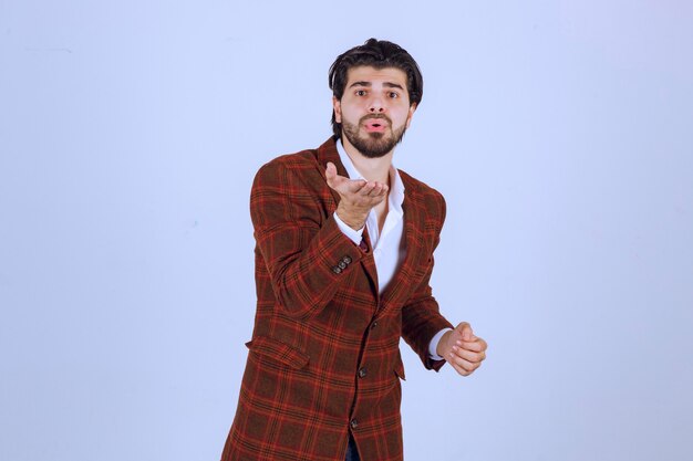 Man in brown blazer greeting someone. 