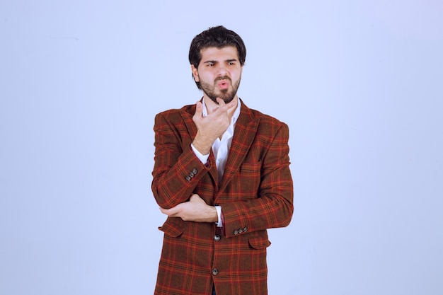 Man in brown blazer pointing and introducing something on the right.