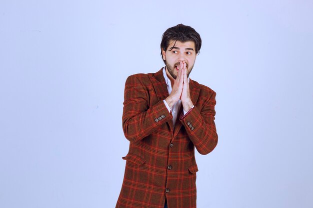 Man in brown blazer uniting his hands and praying. 