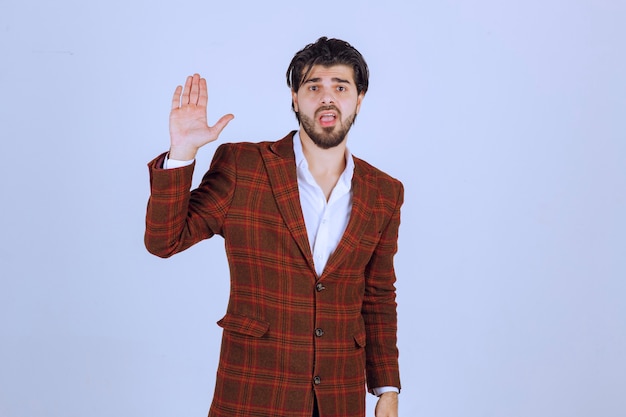 Man in brown jacket raising hand for the attention. 