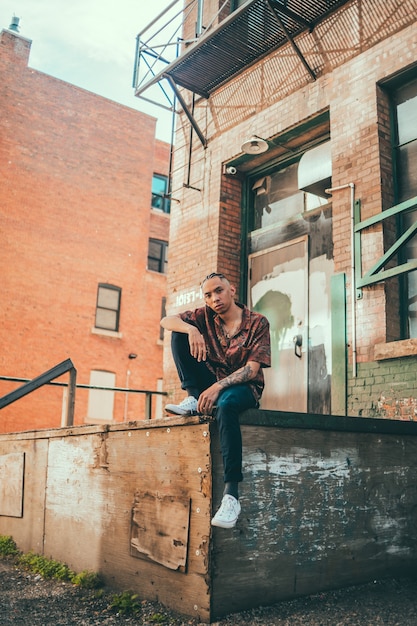 Man in brown jacket sitting on brown wooden bench during daytime