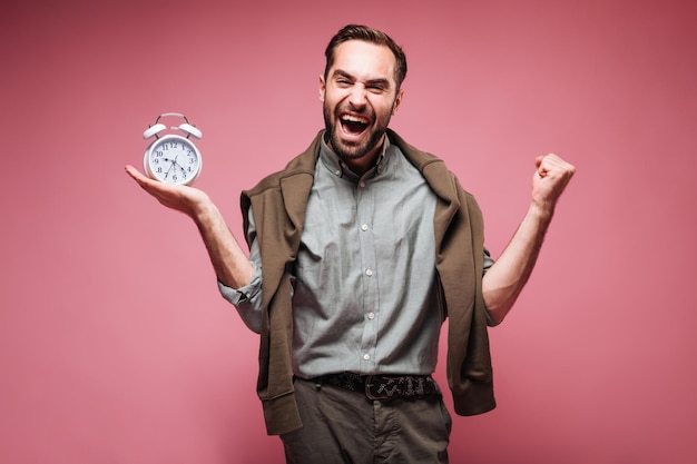 Man in brown outfit happily posing with alarm clock