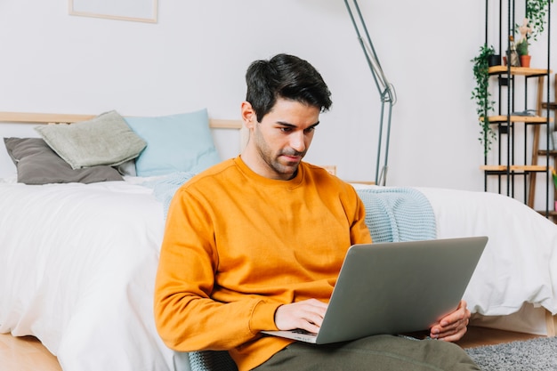 Man browsing laptop near bed