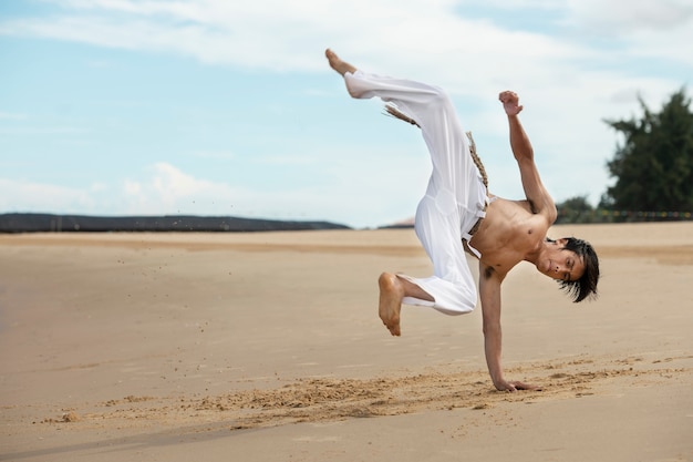 無料写真 一人でカポエイラを練習している浜辺の男