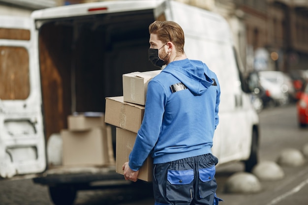 Uomo vicino al camion. ragazzo in uniforme da consegna. uomo in una maschera medica. concetto di coronavirus.