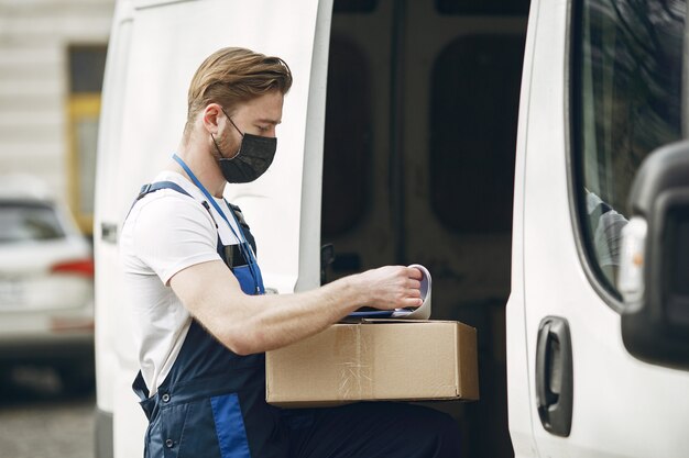 Man by the truck. Guy in a delivery uniform. Man in a medical mask. Coronavirus concept.
