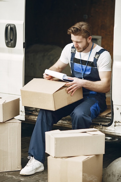 Foto gratuita uomo vicino al camion. ragazzo in uniforme da consegna. uomo con appunti.