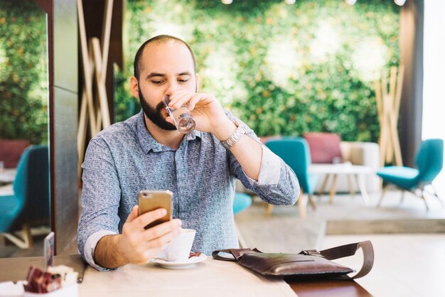 Man in cafe relaxing with phone