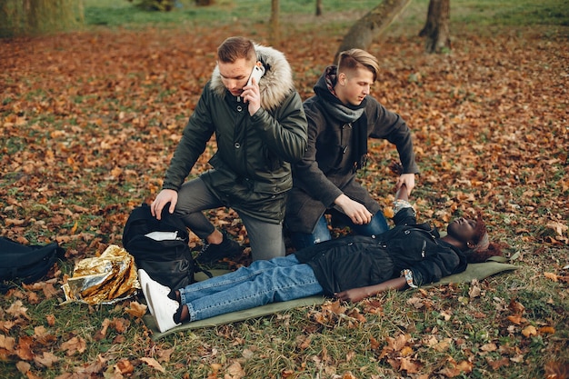 Free photo man calls an ambulance. african girl is lying unconscious. providing first aid in the park