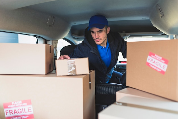 Free photo man in car checking boxes for delivery