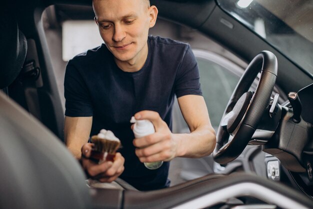 車内のすべての詳細をクリーンアップするためにブラシを使用して車の掃除をする人