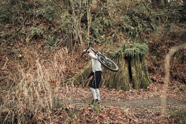 Man carrying bicycle on his back in the forest