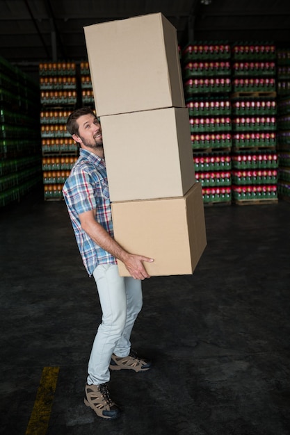 Free photo man carrying cardboard boxes in warehouse