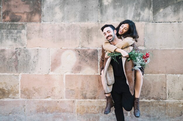 Man carrying woman on back near wall