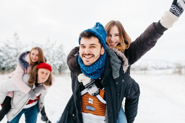 Man carrying woman on back in winter forest 