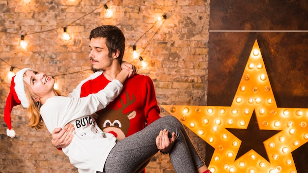 Man carrying woman in front of christmas star decoration