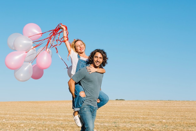 Free photo man carrying woman with balloons