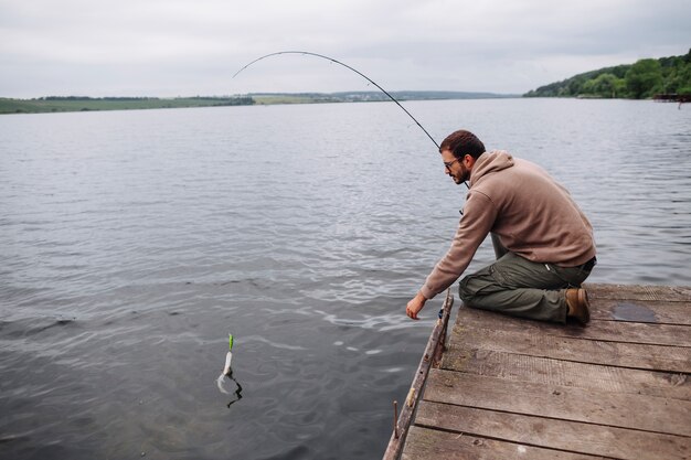Man catching fish with fishing rod in lake