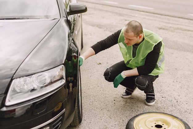 Человек меняет сломанное колесо на автомобиле