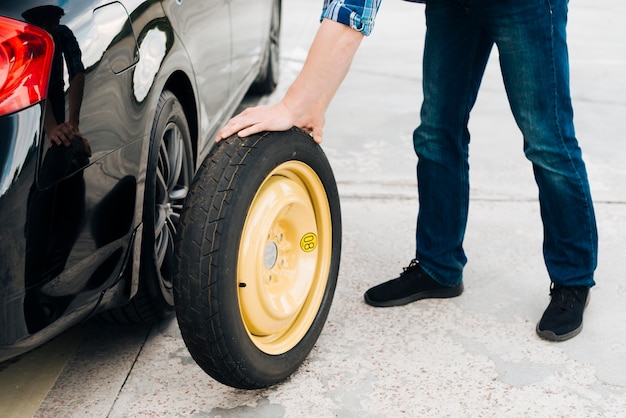 Человек меняется автомобильная шина с запасным колесом