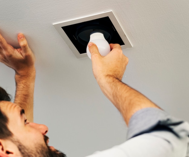 Free photo man changing a light bulb