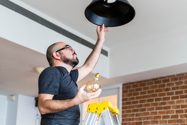 Free photo man changing light bulb