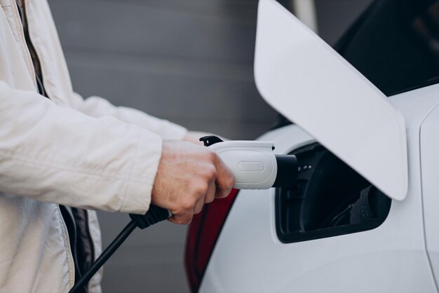 Man charging electric car by the house