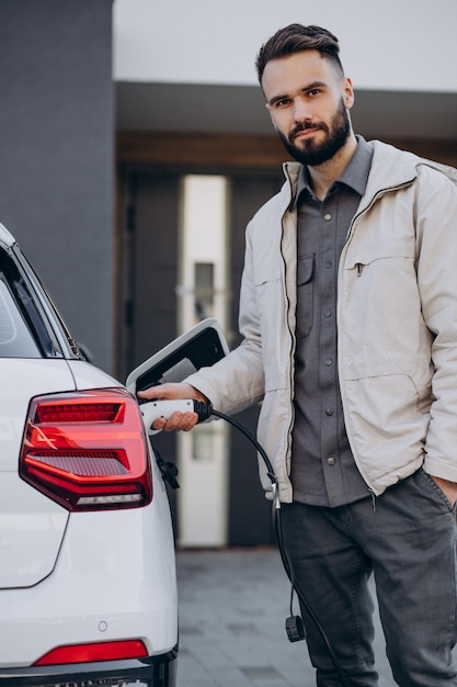 Uomo che carica un'auto elettrica vicino alla casa