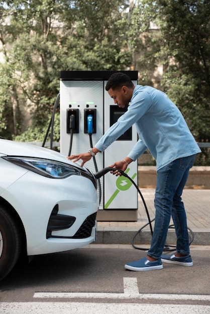 Man charging electric car full shot