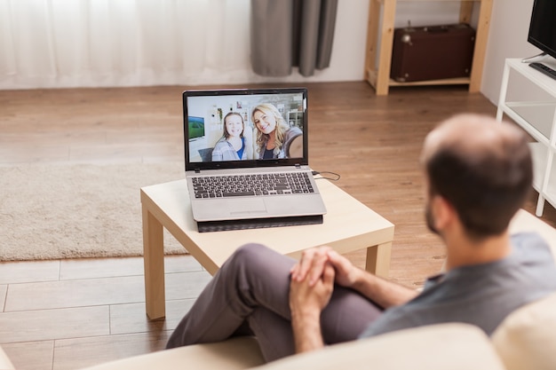 Free photo man chatting with his family during a video call in time of global pandemic.