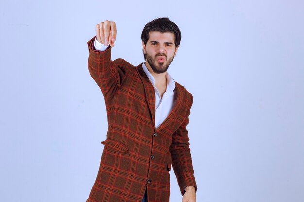 Man in checked jacket adding spices to something.