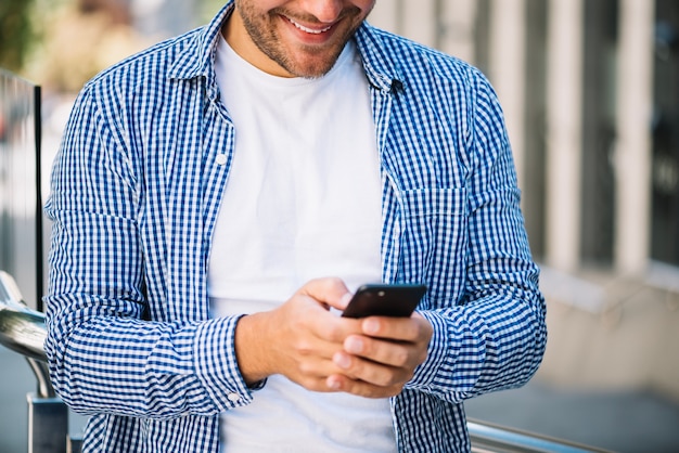 Man in checkered short holding smartphone