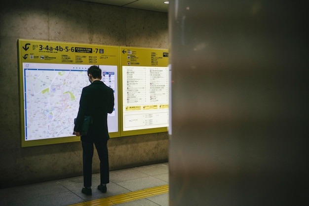 駅の掲示板をチェックする男