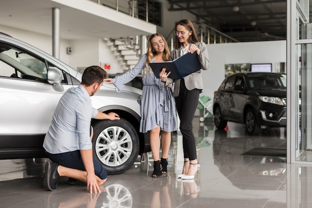 Free photo man checking car tires in a showroom