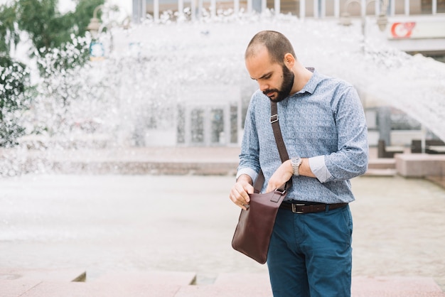 Man checking handbag at street