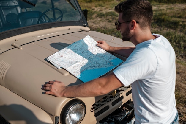 Free photo man checking map while traveling alone by car