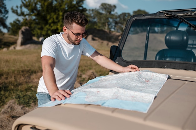 車で旅行中に地図をチェックする男