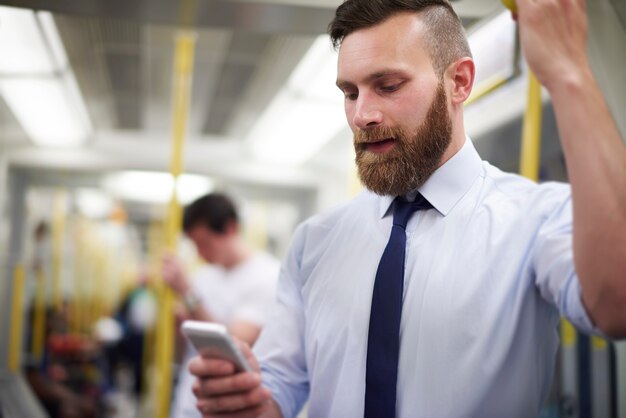 Человек проверяет новости в мобильном телефоне в метро
