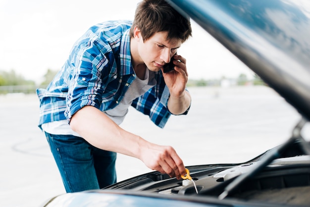 Man checking oil and talking on phone