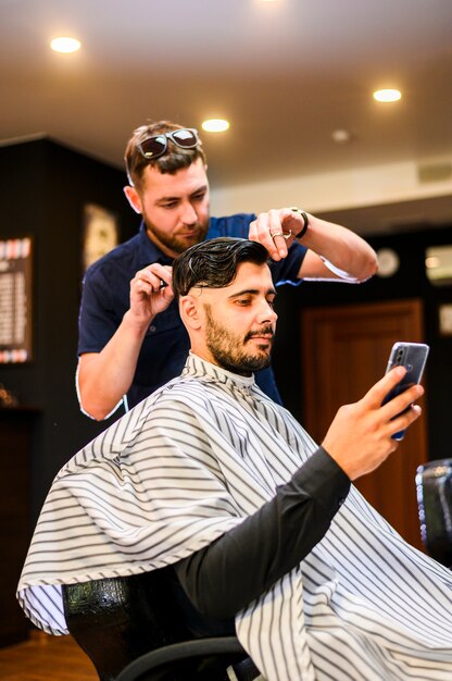 Man checking phone while getting a haircut