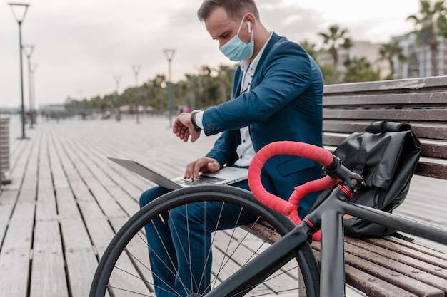 Foto gratuita uomo che controlla l'ora accanto a una bici