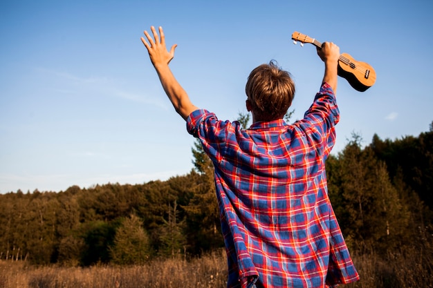 Man cheering and holding ukulele in one hand