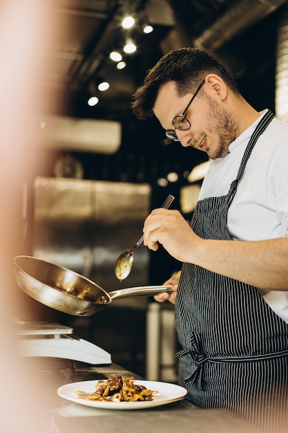 Foto gratuita cuoco unico dell'uomo che cucina pollo asiatico in una cucina del caffè