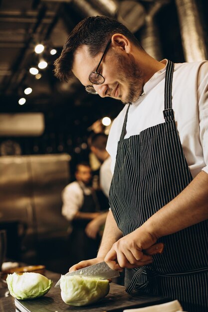 Man chef cutting cabbage at the kitchen restaurant